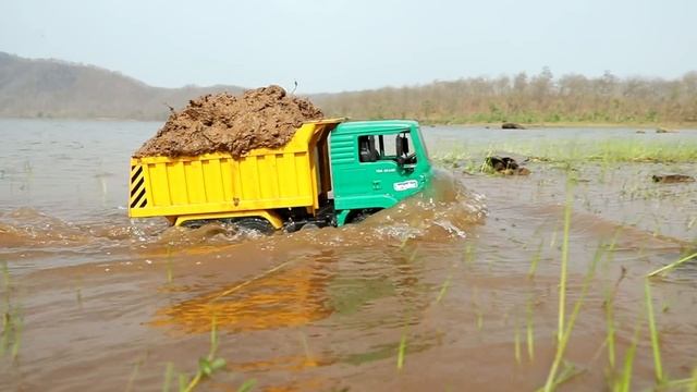 Самосвал с глиной падает в яму, прыгает в воду