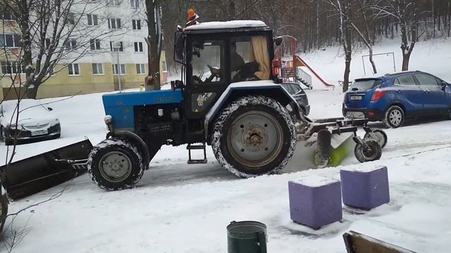 Город завалило снегом. Трактор со щеткой  чистит снег на полном газу.