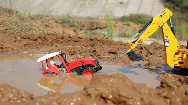 Жёлтый экскаватор вытаскивает трактор с камнями