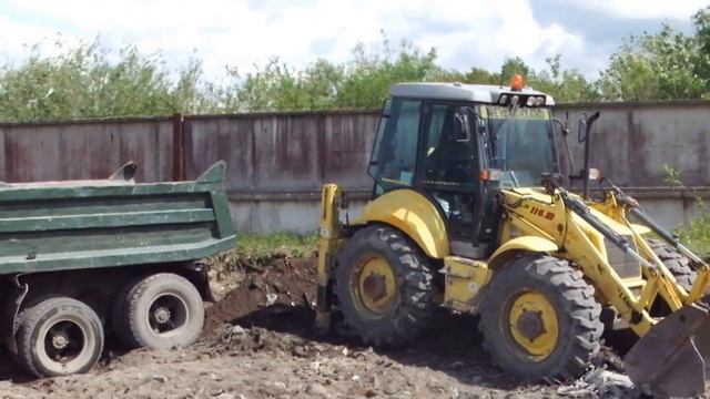 Экскаватор-погрузчик New Holland LB115  грузит самосвал КАМАЗ.