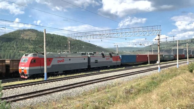 Грузовые поезда РЖД в Восточной Сибири едут вдоль реки Илим и по ЖД-мосту