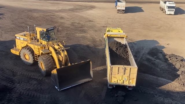 Погрузчик Caterpillar 990 загружает уголь в грузовики.