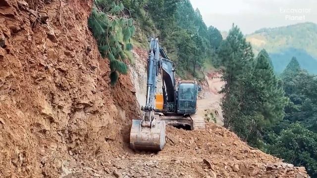 Экскаватор строит дорогу на краю обрыва.