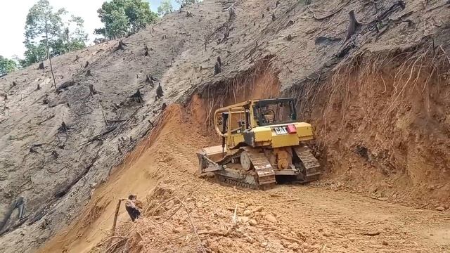 Бульдозер CAT D6R XL прокладывает дорогу на краю пропасти.