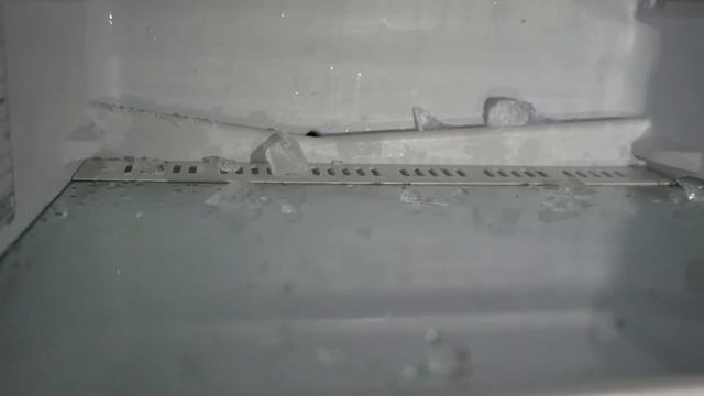 С холодильника течёт вода . Вода внизу холодильника под пластиковой полкой
