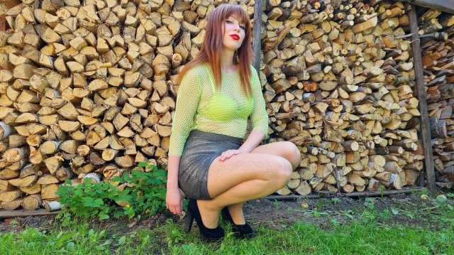 Рыжая длинноволосая милая женщина танцует на высоких каблуках в мини юбке