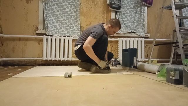 Процесс укладки цельного листа фанеры на старый деревянный пол.